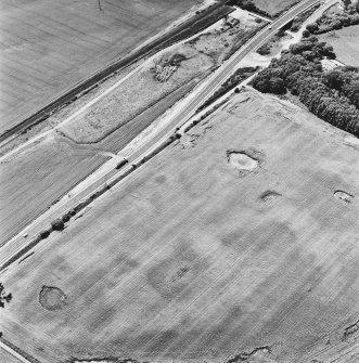 Drumflower, oblique aerial view, taken from the NE, showing the cropmarks of palisaded enclosures, a roman road and quarry pits, and a pit-defined structure and pit-alignment.