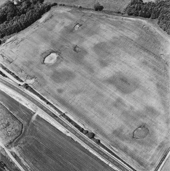 Drumflower, oblique aerial view, taken from the SE, showing the cropmarks of palisaded enclosures, a roman road and quarry pits, and a pit-defined structure and pit-alignment.