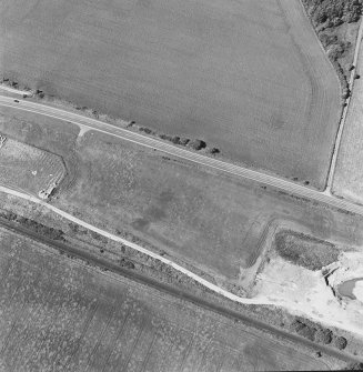 Oblique aerial photograph of Drumflower taken from the S, centred on the cropmarks of barrows, pits and a pit-alignment with the line of a military road to the N.