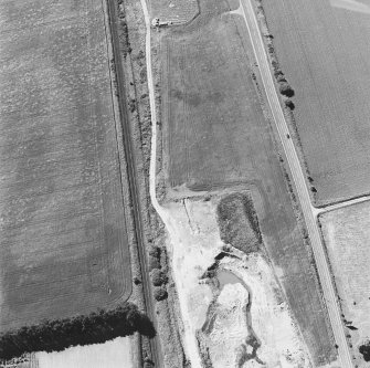 Oblique aerial photograph of Drumflower taken from the SE, centred on the cropmarks of barrows, pits and a pit-alignment with the line of a military road to the N.