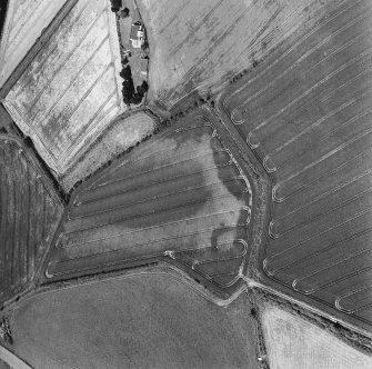 Oblique aerial photograph of Houdston Hill taken from the ESE, centred on the cropmarks of an enclosure and pits.