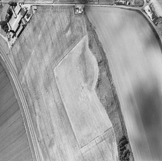 Oblique aerial photograph of Girvan Mains taken from the NW, centred on the cropmarks of a fort.