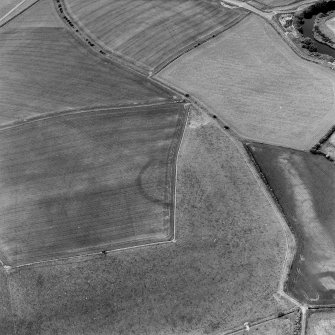 Oblique aerial view centred on the cropmarks of the settlement with enclosure and pits adjacent, taken from the SE.