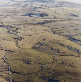 Oblique aerial view centred on the remains of rig with church, burial ground, homestead moat and building adjacent, taken from the NW.