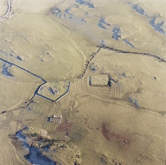 Oblique aerial view centred on the remains of the church, burial ground, homestead moat and building with rig adjacent, taken from the WNW.