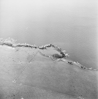 Oblique aerial view centred on the remains of the promontory fort, taken from the WSW.
