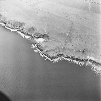 Oblique aerial view centred on the remains of the promontory fort, taken from the NE.