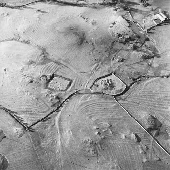 Oblique aerial view centred on the remains of the church, burial ground, homestead moat and building with rig adjacent, taken from the E.