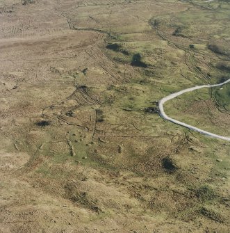 Oblique aerial view centred on the remains of the field-system and small cairns with hut-circle and small cairns adjacent, taken from the NW.