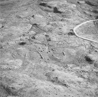 Oblique aerial view centred on the remains of the field-system and small cairns with hut-circle and small cairns adjacent, taken from the NW.