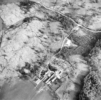 Oblique aerial view centred on the farmsteading and the remains of the township, field-system and castle, taken from the NW.