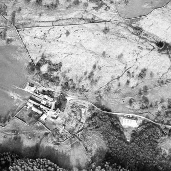 Oblique aerial view centred on the farmsteading and the remains of the township, field-system and castle, taken from the WSW.