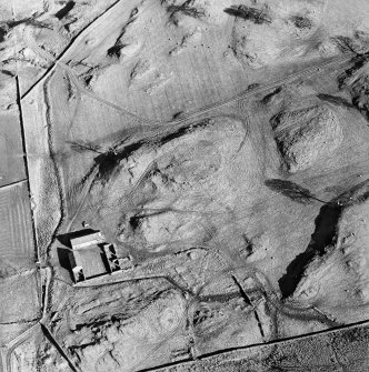 Oblique aerial view centred on the remains of the tower-house, enclosure and farmstead, taken from the WNW.