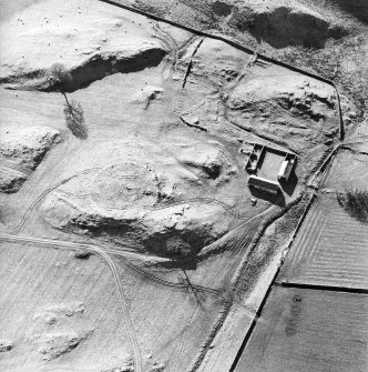Oblique aerial view centred on the remains of the tower-house, enclosure and farmstead, taken from the ENE.
