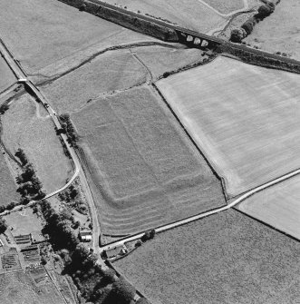 Oblique aerial view of Birrens, taken from the N, centred on a Roman Fort.  A watermill, situated to the E of the fort is visible in the bottom right-hand corner of the photograph.