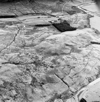 Raeburnfoot, oblique aerial view, taken from the WNW, centred on the bank barrow. Raeburnfoot Roman Fort, and enclosures at Kiln Syke, are visible in the top half of the photograph.