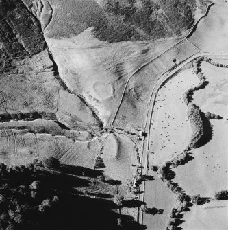 Oblique aerial view of Fiddleton centred on the remains of two scooped settlements, cultivation terraces and a cottage, taken from the SSE.