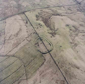 Oblique aerial view centred on the remains of the fort and palisaded enclosure with field-system, rig, boundary banks, enclosures and lazy beds adjacent, taken from the NE.