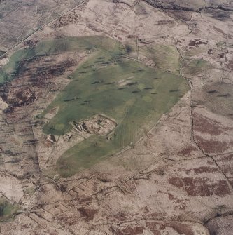 Oblique aerial view centred on the remains of the settlement and quarries with farmstead, buildings, enclosure, boundary banks and rig adjacent, taken from the NW.