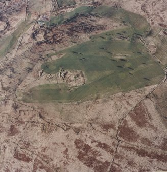 Oblique aerial view centred on the remains of the settlement and quarries with farmstead, buildings, enclosure, boundary banks and rig adjacent, taken from the NNW.