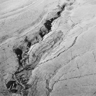 Oblique aerial view of Thief Sike centred on the remains of a township, field-system, rig, quarry and pens with a possible hut-circle, cultivation terraces, small cairns and shieling huts and a possible sheepfold adjacent, taken from the SE.