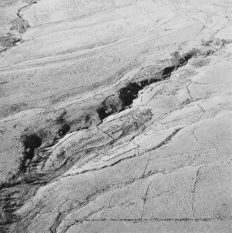 Oblique aerial view of Thief Sike centred on the remains of a township, field-system, rig, quarry and pens with a possible hut-circle, cultivation terraces, small cairns and shieling huts and a possible sheepfold adjacent, taken from the E.