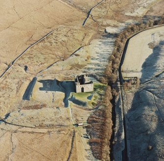 Oblique aerial view of Hermitage Castle centred on the remains of a castle and earthwork castle, taken from the W.
