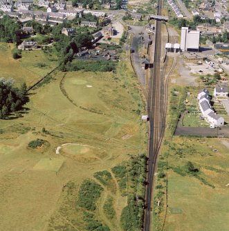 Oblique aerial view of the remains of Muir of Ord henge, Castle Hill.
