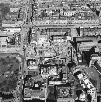Oblique aerial view centred on the construction of the shop and bus station with the bank adjacent, taken from the SSE.