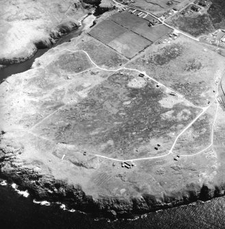 Oblique aerial view centred on the remains of the radar station with caves and crofting township adjacent, taken from the NNW.