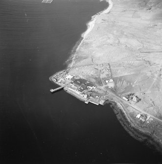 Oblique aerial view centred on the factory and laboratory with the pier and remains of lazy beds adjacent, taken from the SE.