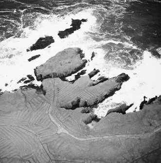 Oblique aerial view centred on the remains of the settlement with the remains of lazy beds adjacent, taken from the SW.