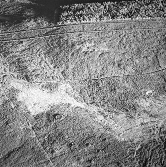 Tormore, oblique aerial view, taken from the W, centred on a hut-circle. A further hut-circle is visible in the centre right of the photograph.