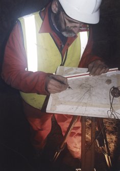 Commission at work: Mr I Parker with plane table on half-landing of subterranean structure.