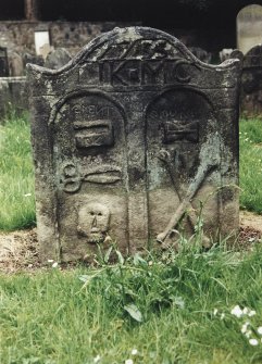 Tulliallan, Old Parish Church, burial ground.
General view of gravestone with two carved arches, enclosing (left) pressing iron and scissors (the tools of a tailor) and a skull; (right) Hour-glass and crossed bones.
Insc: '1755. I.K. M.C'. and 'Memento Mori'.