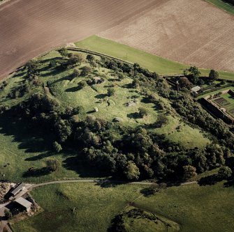 Oblique aerial view centred on the remains of the vitrified fort and broch, taken from the WNW.