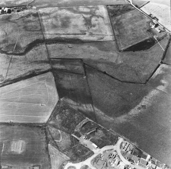 Oblique aerial view of Kintore centred on the cropmarks of the SW angle of the Roman temporary camp and several round-houses.
