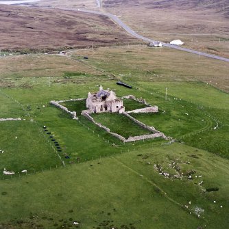 Oblique aerial view centred on the ruins of the Laird¿s House with the remains of the broch adjacent, taken from the NW.