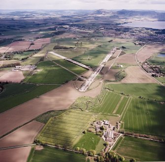 General oblique aerial view looking across the farmsteading, airfield and radio station towards Kinross, taken from the WSW.