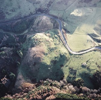 Oblique aerial view centred on the remains of the fort with the remains of the cairn adjacent, taken from the NNE.