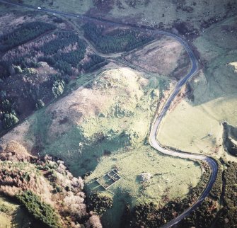 Oblique aerial view centred on the remains of the fort with the remains of the cairn adjacent, taken from the NW.