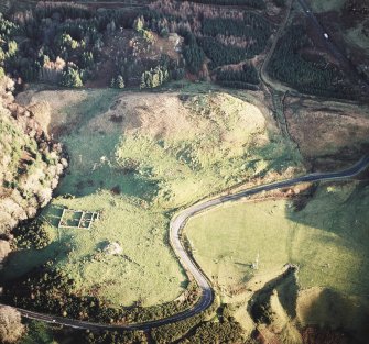 Oblique aerial view centred on the remains of the fort with the remains of the cairn adjacent, taken from the W.