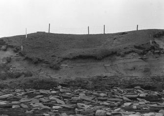 Photograph showing coastal erosion of structural features.