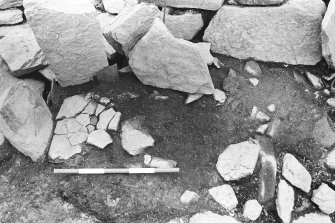 Excavation photograph : trench G - detail of hearth L275 after removal of fallen orthostat.

(see MS/682/120 for detailed description)
