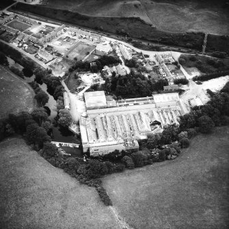 Oblique aerial view from the W, showing works, workers' housing and the weir.