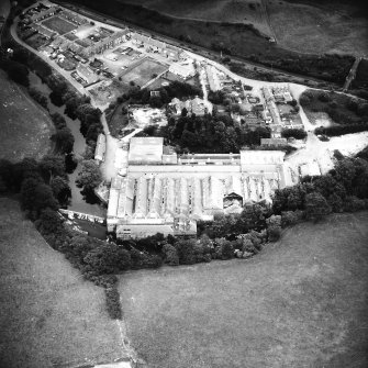 Oblique aerial view from the WSW, showing works, workers' housing and the weir.