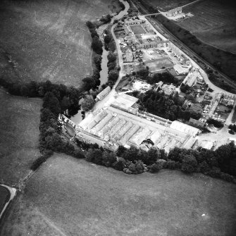Oblique aerial view from the SW, showing works, workers' housing and the weir.