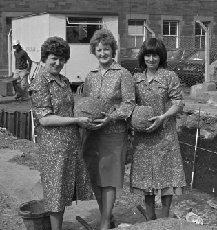 View of three women holding stones.