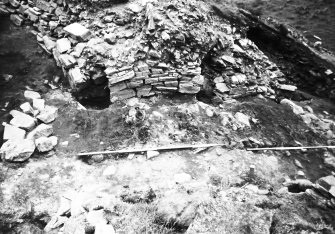 Excavation photograph showing view outward through entrance way, crossways timbers originally extended to right of ranging rods ( cut away during 1973 excavation)

