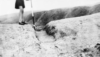 Excavation photograph: Portcullis trench and ranging rod at an angle.